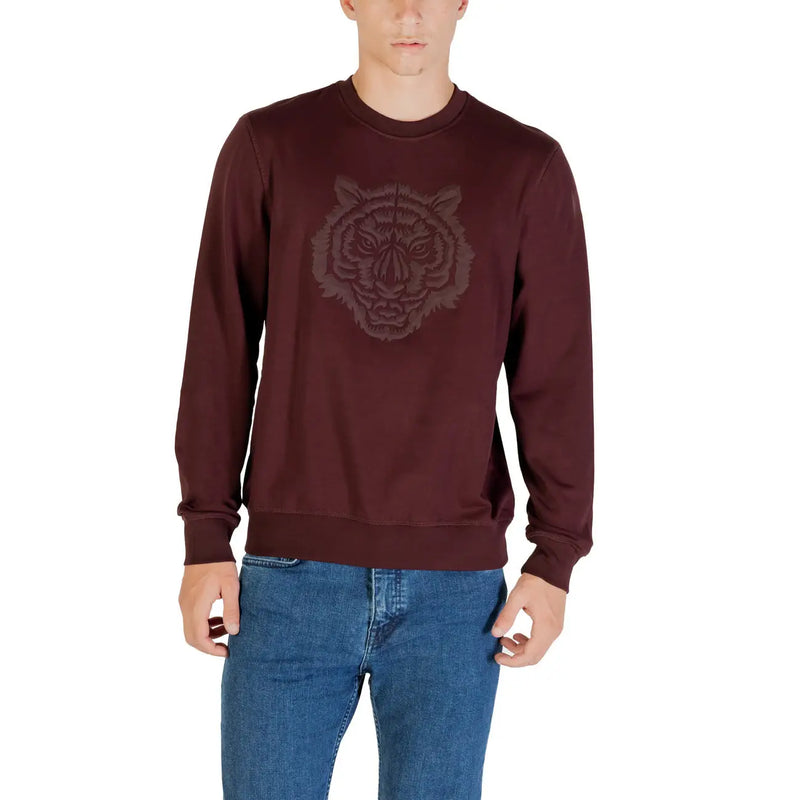 Ein bordeauxrotes Herren-Sweatshirt mit gesticktem Tigerkopf-Motiv, kombiniert mit blauen Jeans.