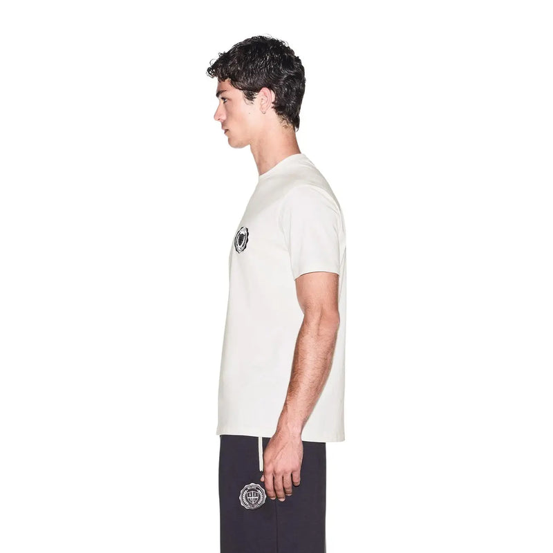 Armani Exchange Weißes Herren-T-Shirt aus Baumwolle mit kurzen Ärmeln und schwarzem, rundem Logo, kombiniert mit einer marineblauen Hose mit Stickerei.