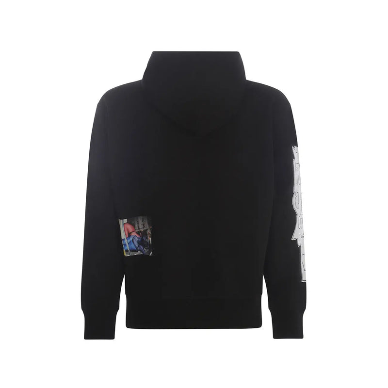 Schwarzer Kapuzenpullover mit kleinem rechteckigem Fotoaufnäher auf der linken Brust und weißem Grafikdesign auf dem rechten Ärmel