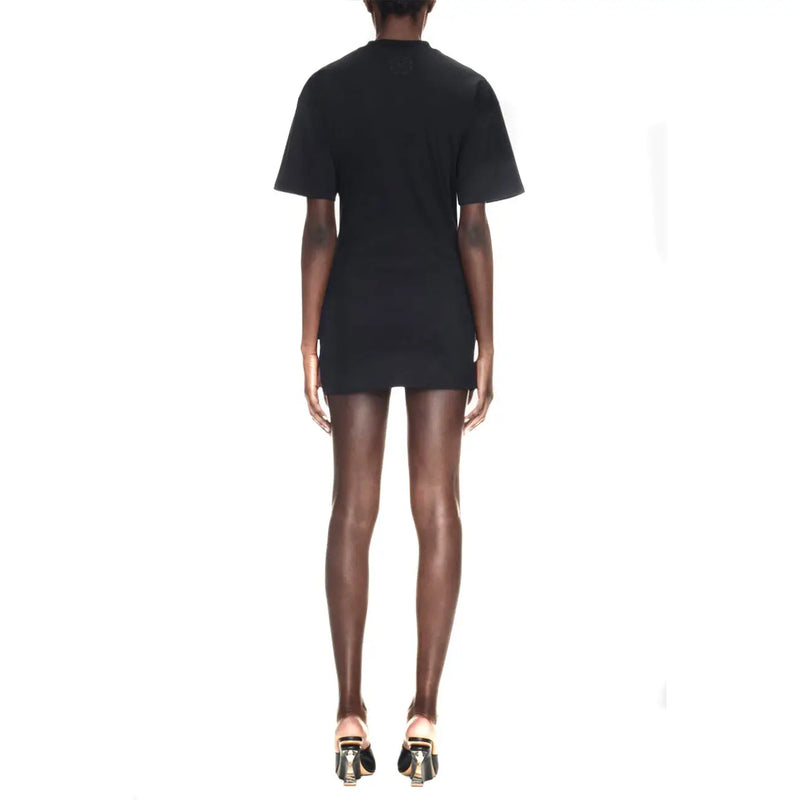 Black short-sleeved mini dress with a simple fitted silhouette paired with sculptural heels and knotted detail