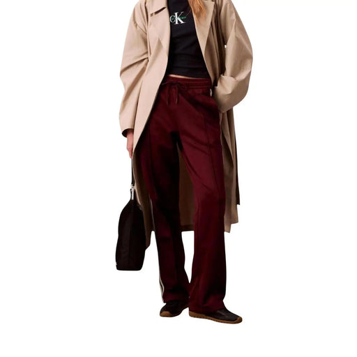 Woman wearing beige trench coat black Calvin Klein T-shirt and Bordeaux Lace Trousers