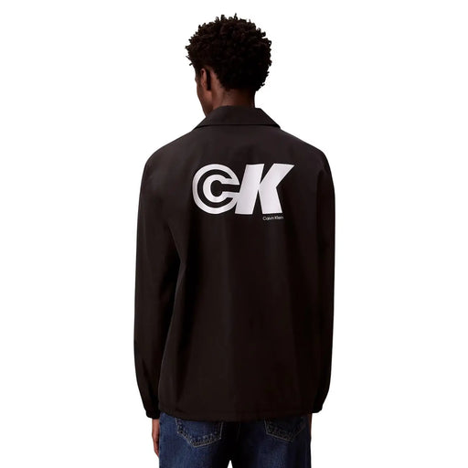 Rückansicht einer schwarzen Calvin Klein Coach-Jacke mit markantem weißen CK-Logo im klassischen Polyester-Blazer-Stil
