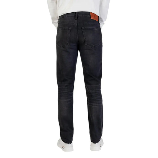 Dark-wash slim fit Calvin Klein cotton jeans for men with black zip button and brown leather brand patch at waistband