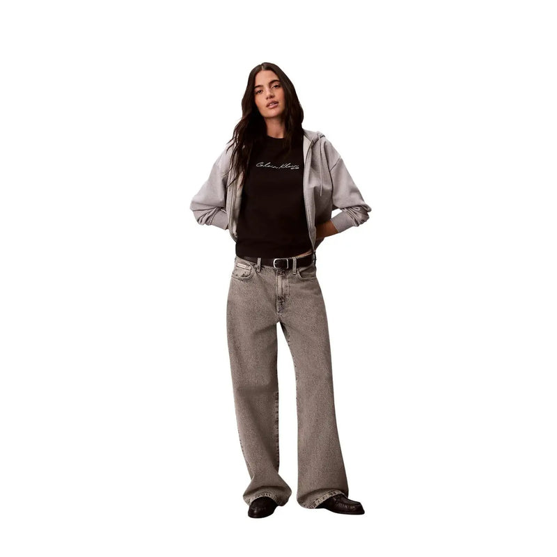 Weit geschnittene graue Jeans mit verwaschenem Look und dezenter Struktur, kombiniert mit einem schwarzen Baumwoll-T-Shirt von Calvin Klein Jeans für Damen mit Rundhalsausschnitt.