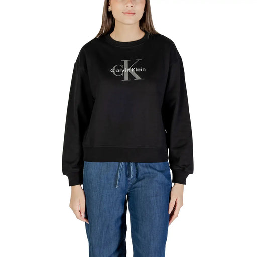 Woman wearing a black Calvin Klein long-sleeved sweatshirt and blue denim drawstring pants