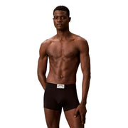 Schwarze Calvin Klein Herren-Baumwollslips mit weißem Bundetikett, verpackt in einer grünen Baumwoll-Unterwäschebox.