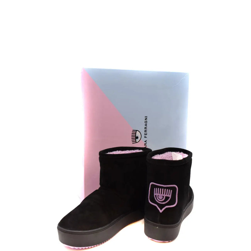 Schwarze Wildleder-Ankle-Boots mit pinkfarbenem, gesticktem Augenlogo von Chiara Ferragni, ausgestellt vor einer Markenbox.