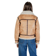Bomberjacke aus hellbraunem Shearling mit flauschigen weißen Fleecekragen und -bündchen sowie dunkelbraunem Lederbesatz, kombiniert mit einem beigen Polyesterblazer.