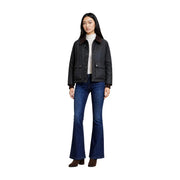 Schwarze Lederjacke mit braunem Shearling-Kragen und Pattentaschen, kombiniert mit einem choralgrünen Baumwollblazer mit klassischer Reißverschlusstasche.
