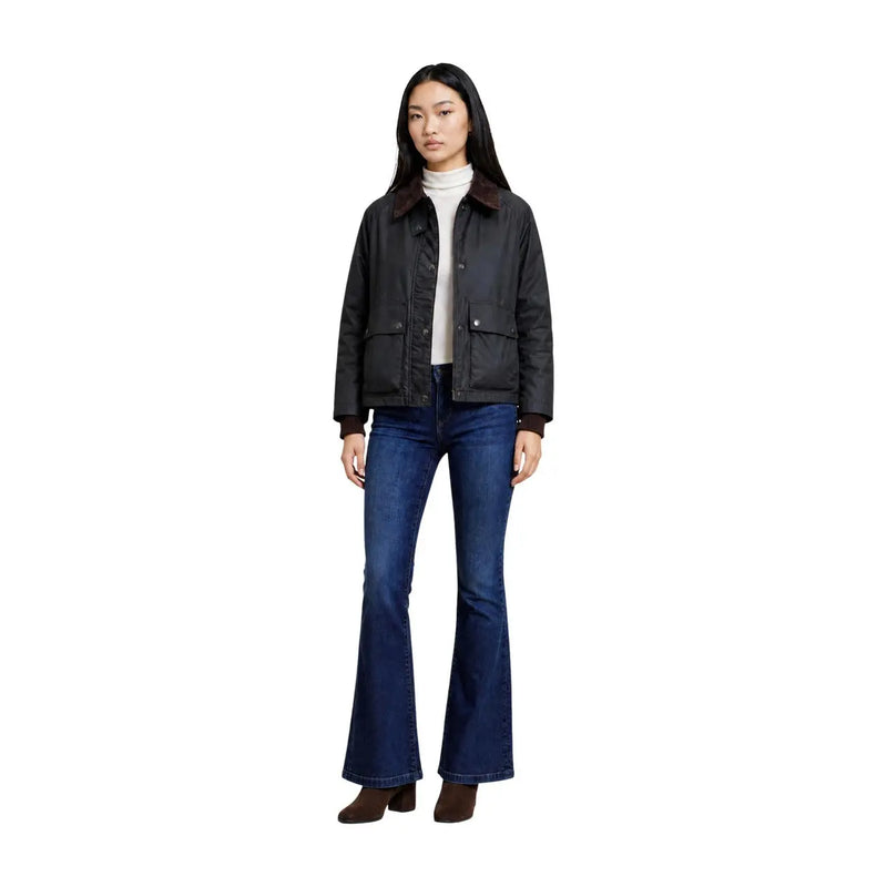 Schwarze Lederjacke mit braunem Shearling-Kragen und Pattentaschen, kombiniert mit einem choralgrünen Baumwollblazer mit klassischer Reißverschlusstasche.
