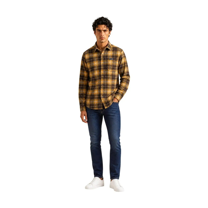 Ein Mann, der einen Columbia braune Herrenhemdjacke aus kariertem Polyester mit kleinem Brustlogo und dunkelblauer Jeans