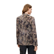 Eine Frau trägt einen beigefarbenen Polyesterblazer von Desigual mit langen Ärmeln und einem eleganten, dezenten Blumenmuster.