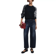 Eine leuchtend rote, glänzende Lederclutch mit silbernen Nieten und Kettenriemen, abgebildet mit einem Strickpullover von Desigual für Damen.