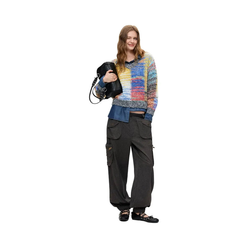 Frau trägt einen roten Desigual-Strickpullover aus Wollmischung mit farbenfrohem Strukturmuster, dazu Jeans und Cargohosen.