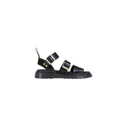 Schwarze Dr. Martens Damen-Sandalen aus Leder mit goldfarbenen Schnallen und einer von hinten sichtbaren, klobigen Gummisohle.