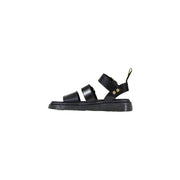 Schwarze Dr. Martens Damen-Sandalen aus Leder mit Schnalle, klobiger Sohle und goldfarbenen Beschlägen, von der Rückseite gesehen