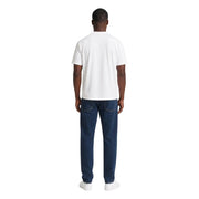 Ein Mann trägt ein weißes ea7 Herren-Baumwoll-T-Shirt in klassischer Passform und dunkelblaue Jeans.