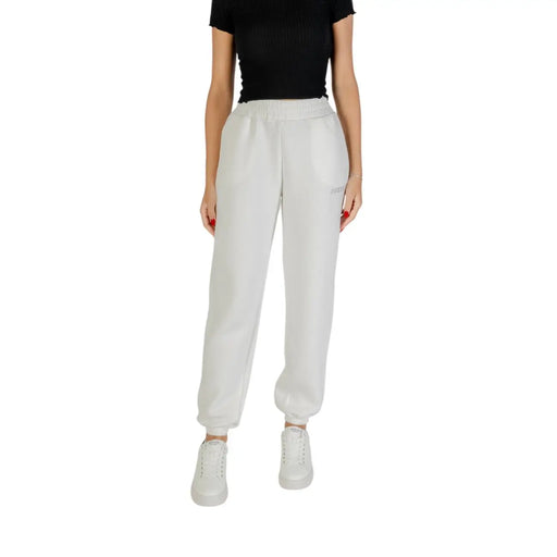 Woman wearing Guess Active Black Printed Trousers with Laces, light gray sweatpants, and white sneakers