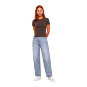 Eine Frau trägt ein dunkelgraues Guess Active Braunes, kurzes Chara-T-Shirt aus Viskose mit hellen, weit geschnittenen Jeans.