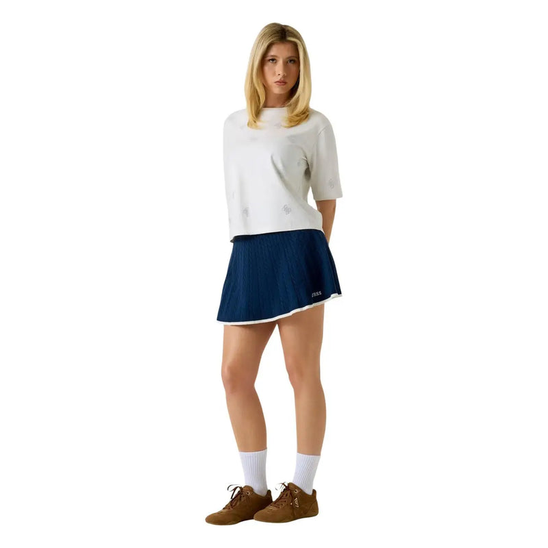 Guess Damen-Tennisrock in Marineblau mit Falten, weißem Besatz und schwarzem Logo, kombiniert mit einem weißen Baumwoll-T-Shirt mit Strasssteinen