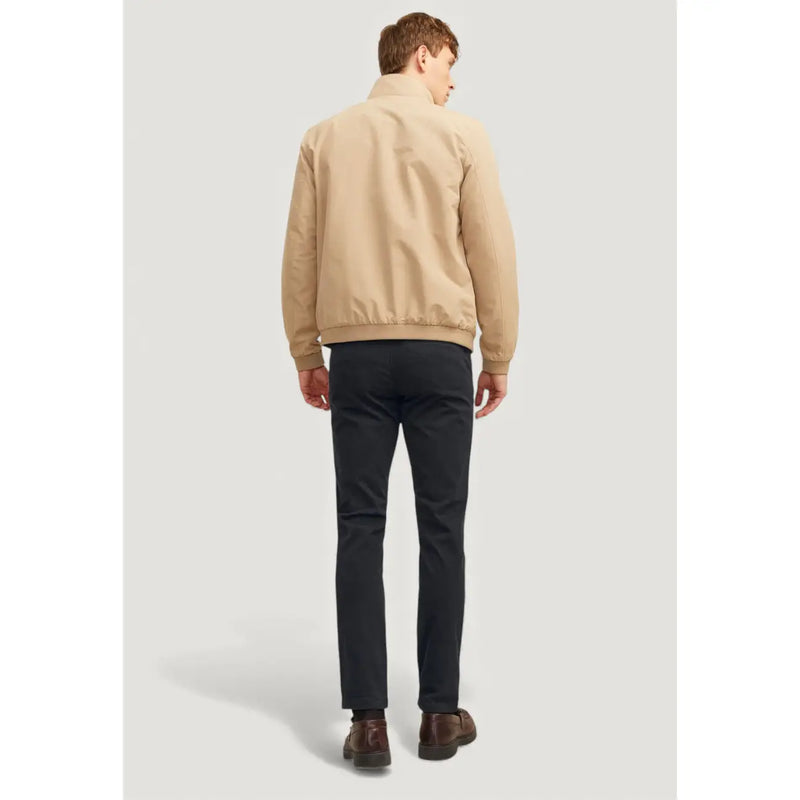 Beige Bomberjacke mit klassischem Kragen und gerippten Bündchen, kombiniert mit einer schwarzen Baumwollhose von Jack & Jones für Herren.