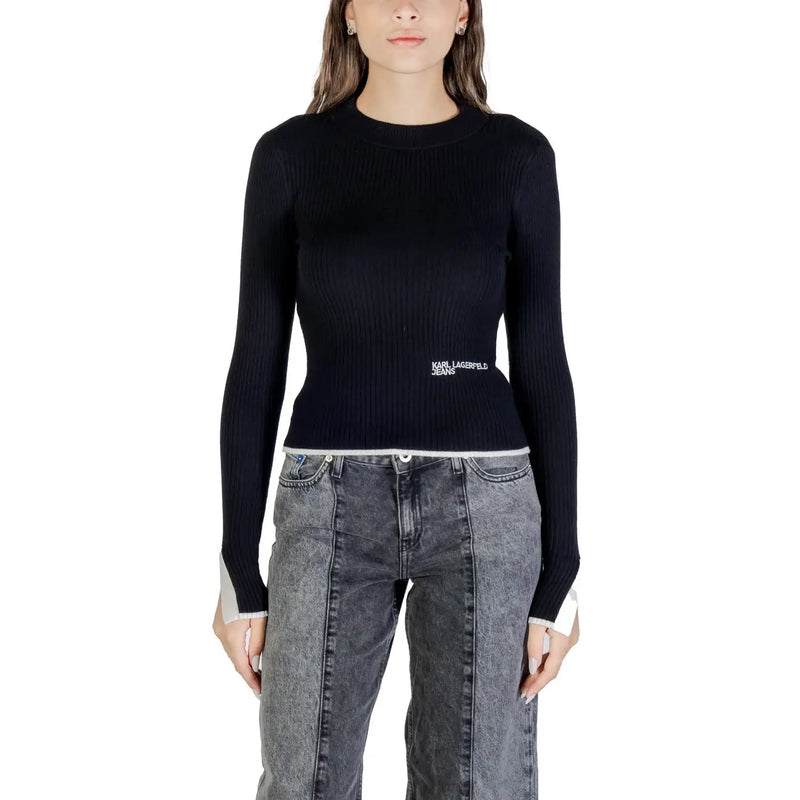 Women wearing black ribbed long-sleeve top with white trim and dark gray patchwork jeans