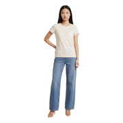 Eine Frau trägt ein beigefarbenes, kurzes Baumwoll-T-Shirt von Liu Jo mit Rundhalsausschnitt und gesticktem Logo sowie hellblaue Jeans.
