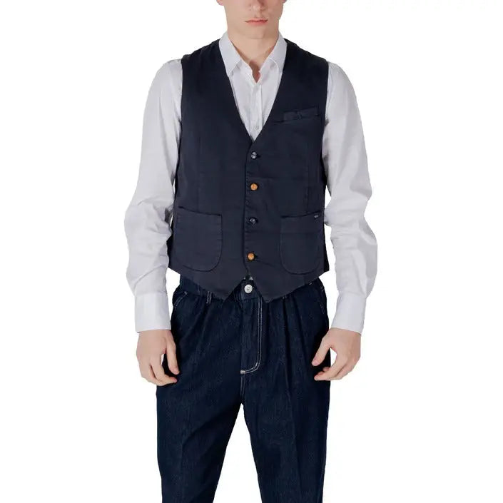 Man wearing a navy vest over a white shirt in a stylish ensemble