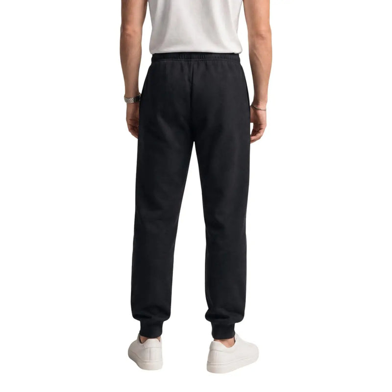 Schwarze Jogginghose aus Baumwollfleece von The North Face für Herren mit elastischem Bund und gerippten Bündchen, von hinten gesehen.