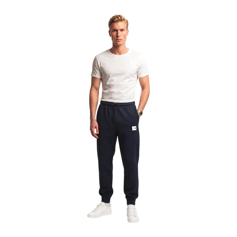 Die schwarzen Baumwollfleecehosen von The North Face für Herren in Marineblau verfügen über einen weißen Logoaufnäher und elastische Bündchen.