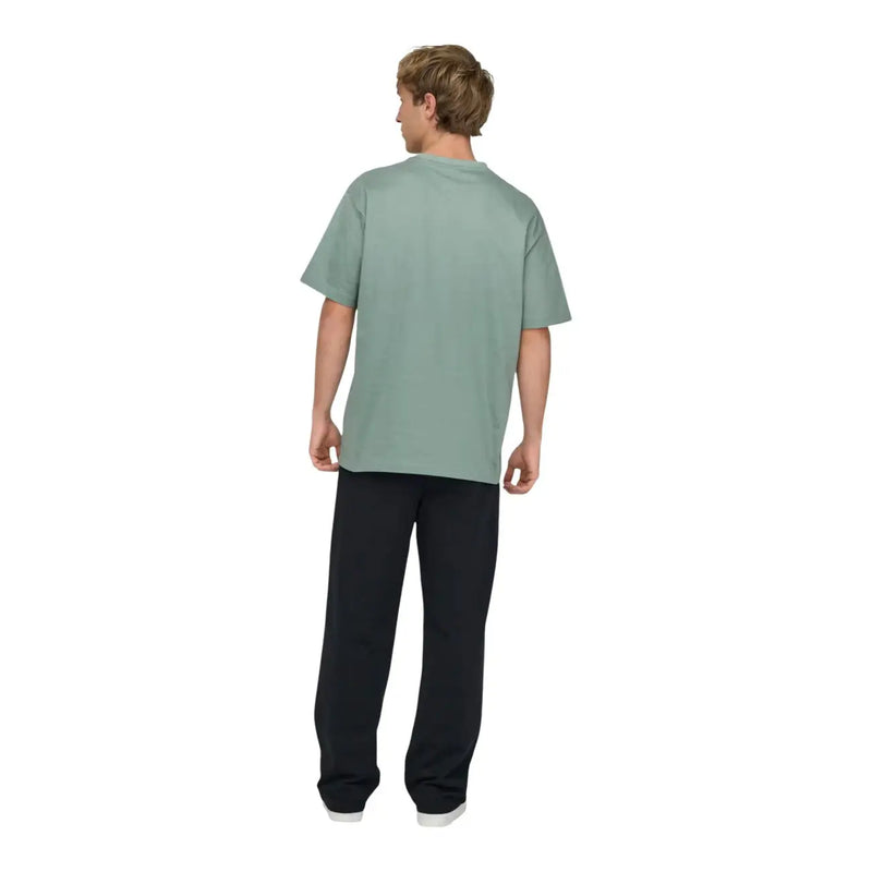 Ein Mann, der einen only grünes Baumwoll-T-Shirt von and sons für Herren mit lockerer Passform und in einem sanften, gedeckten Salbeigrün.