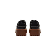 Timberland Schwarze Damen-Plateauschuhe aus Leder, bestehend aus schwarzen Lederloafers mit klobigen braunen Gummisohlen und weißen Ziernähten.