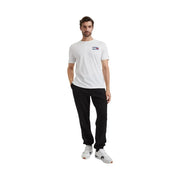 Weiß Tommy Hilfiger t-shirt mit einem kleinen rechteckigen Logo auf der Brust, kombiniert mit einer schwarzen Fleecehose aus Baumwollmischgewebe
