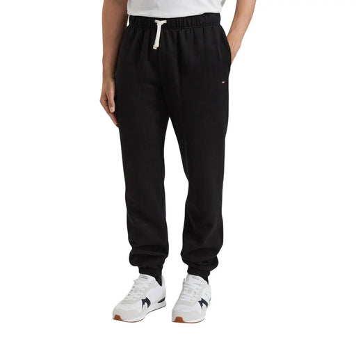 Schwarze Tommy Hilfiger Herren-Fleecehose aus Baumwollmischgewebe mit weißem Kordelzug und dezentem Logo am Oberschenkel (Vorderansicht)