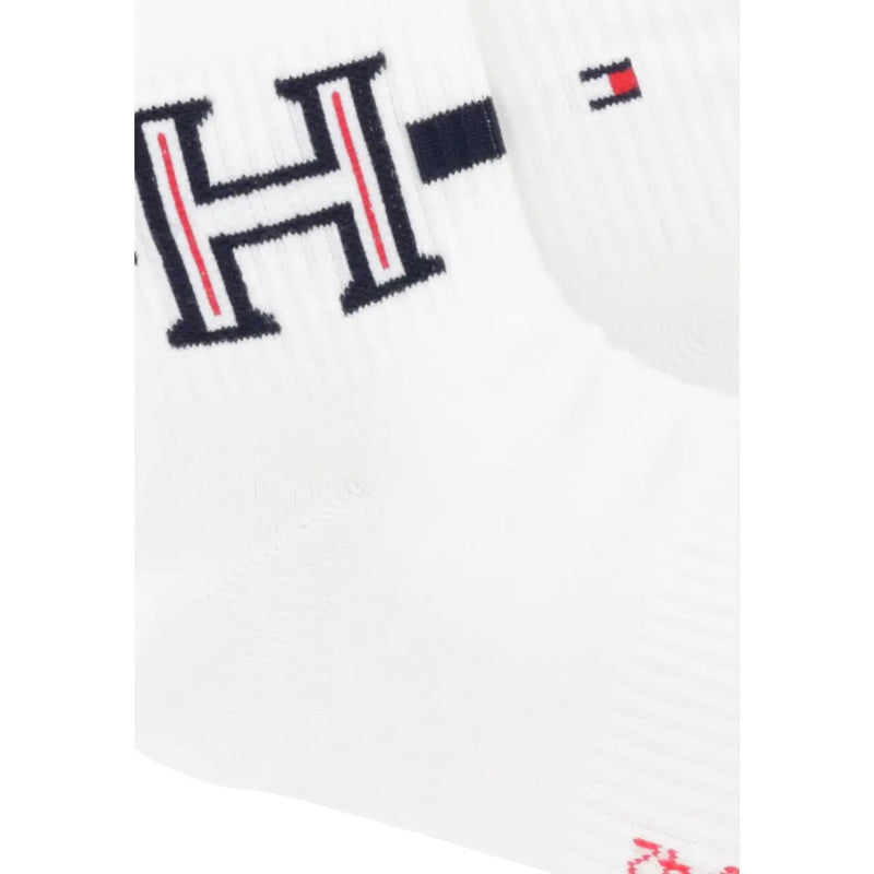 Weiße Stricksocke mit auffälligem schwarzem H-Logo, roten Streifen und Tommy-Hilfiger-Flaggenemblem, passend zu Herrenboxershorts.