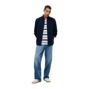 Tommy Hilfiger Herren-Jeanshemd aus blauer Baumwolle, lässig kombiniert mit einem dunkelblauen Button-Down-Hemd und einem gestreiften T-Shirt über hellen Jeans.