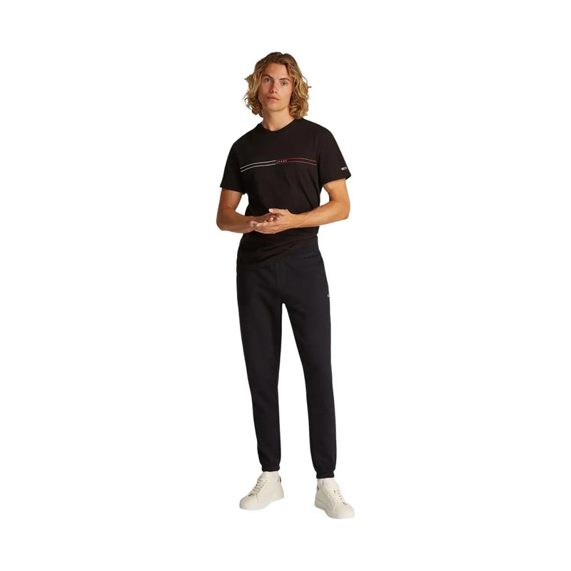 Tommy Hilfiger Herren-Fleecehose in Schwarz, schmal geschnitten, kombiniert mit einem schwarzen t-shirt mit weißen und rosa Streifen