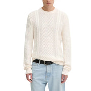 Cream cable knit sweater with black belt and light blue jeans.