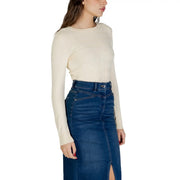 Eine Frau trägt einen cremefarbenen, langärmeligen, rundhalsigen Viskosepullover. top kombiniert mit einem dunkelblauen Jeansrock